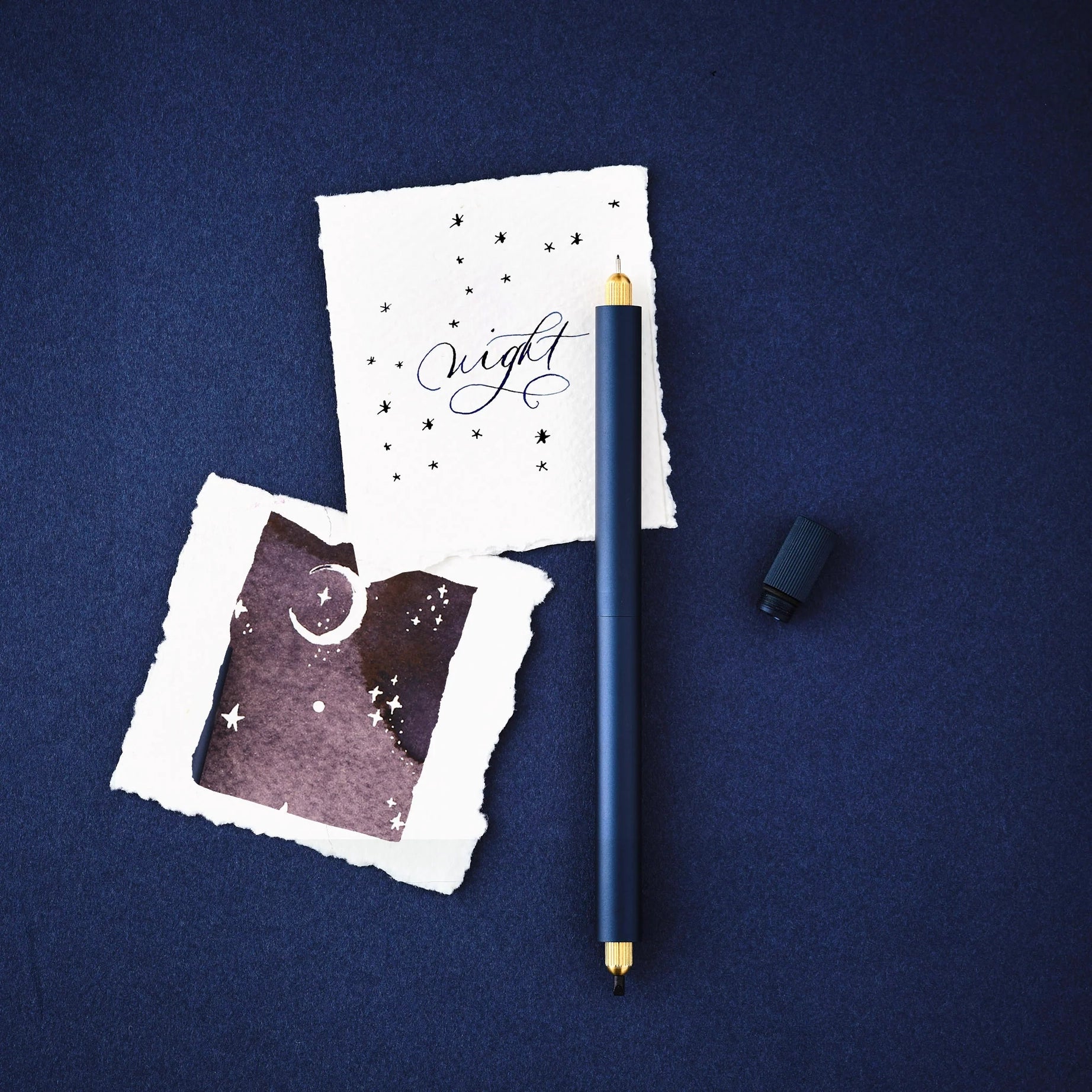 Tom’s Studio Lumos Pro Duo Midnight Pen with "night" star and moon sheets, elegant stationery set on dark blue background.