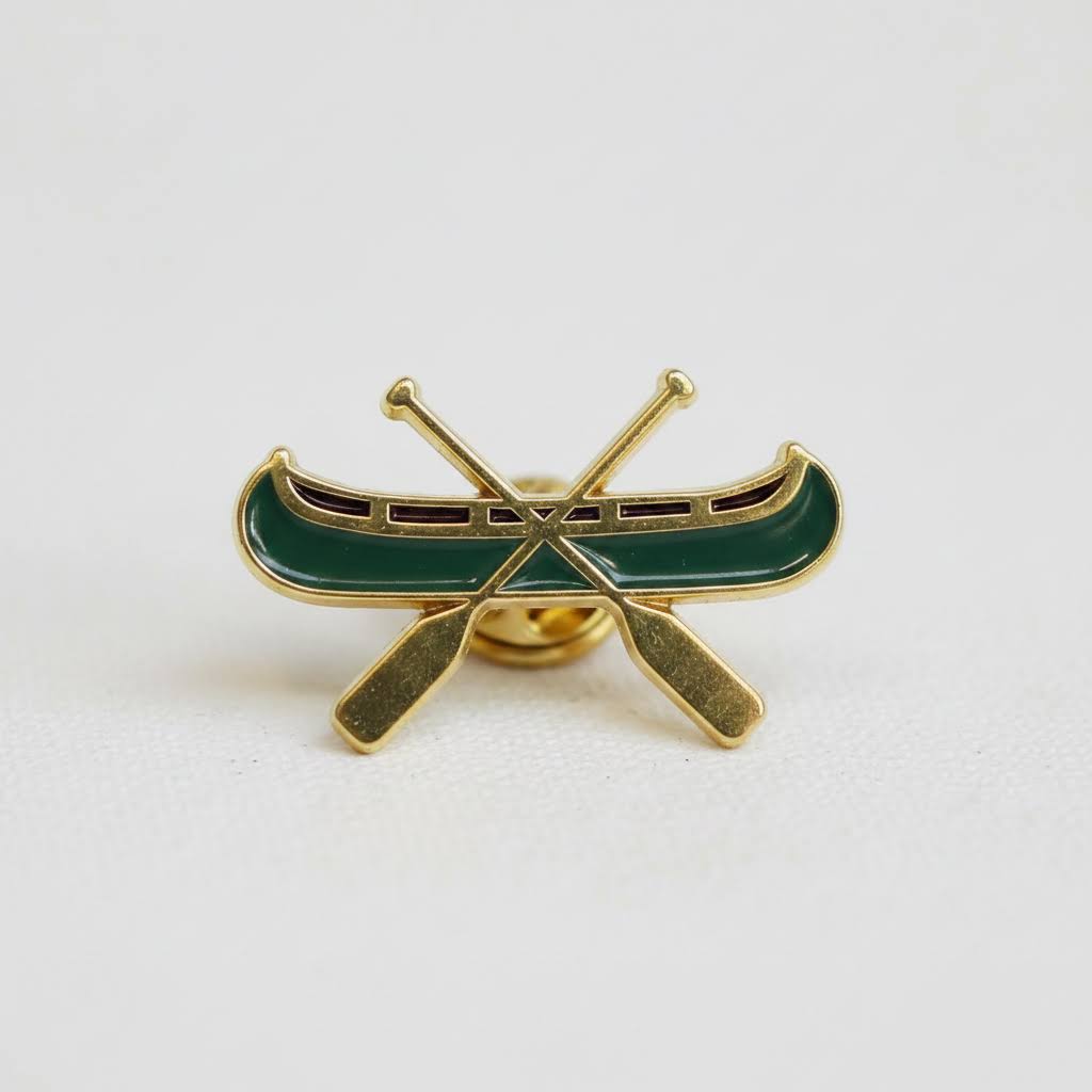 Forager Provisions LTD The Wild Wander canoe enamel pin in green and gold with crossed paddles design.