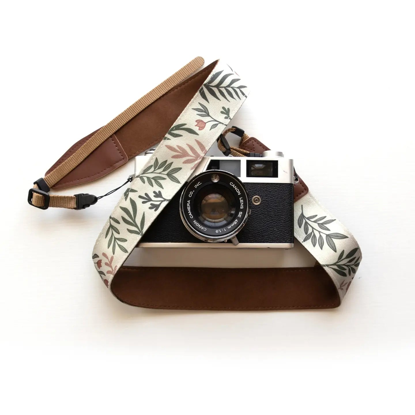 Stylish camera with Wildtree Moody Flower strap and brown leather accents on white background, perfect camera accessory.