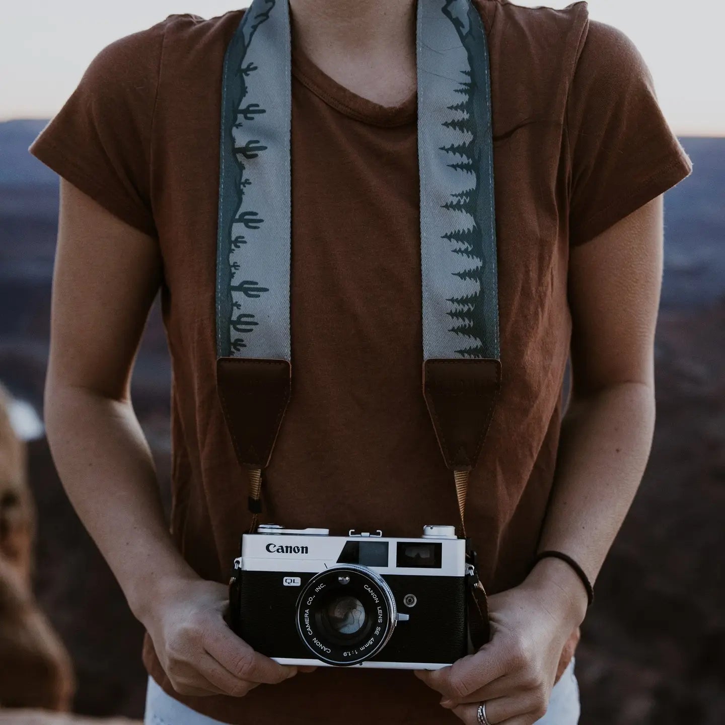 Person in brown shirt using vintage Canon camera with Wildtree Landscape Camera Strap by Wildtree, ideal for photographers.