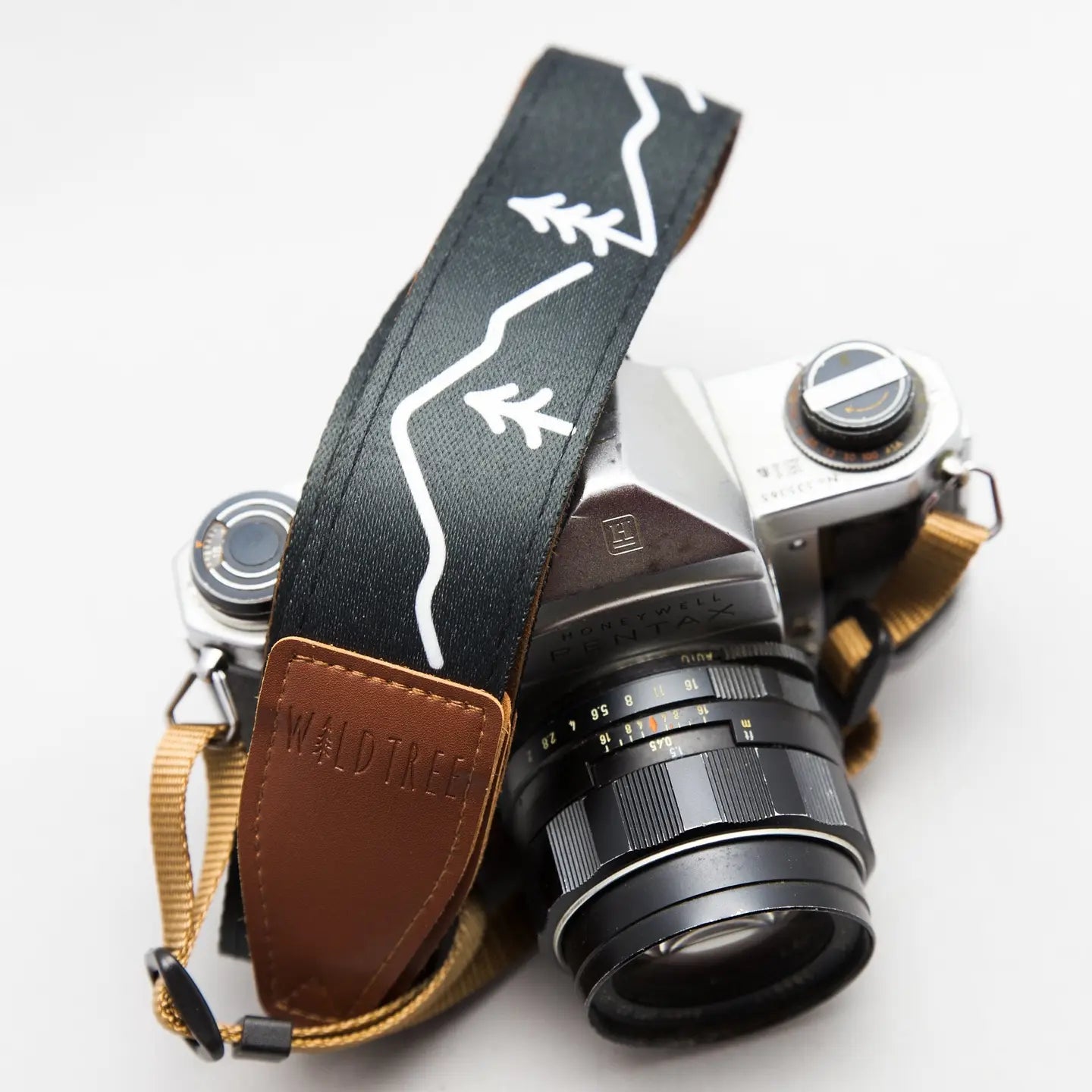 Vintage film camera with Wildtree Simple Mountain strap, tan leather detail, on clean white background photography gear.