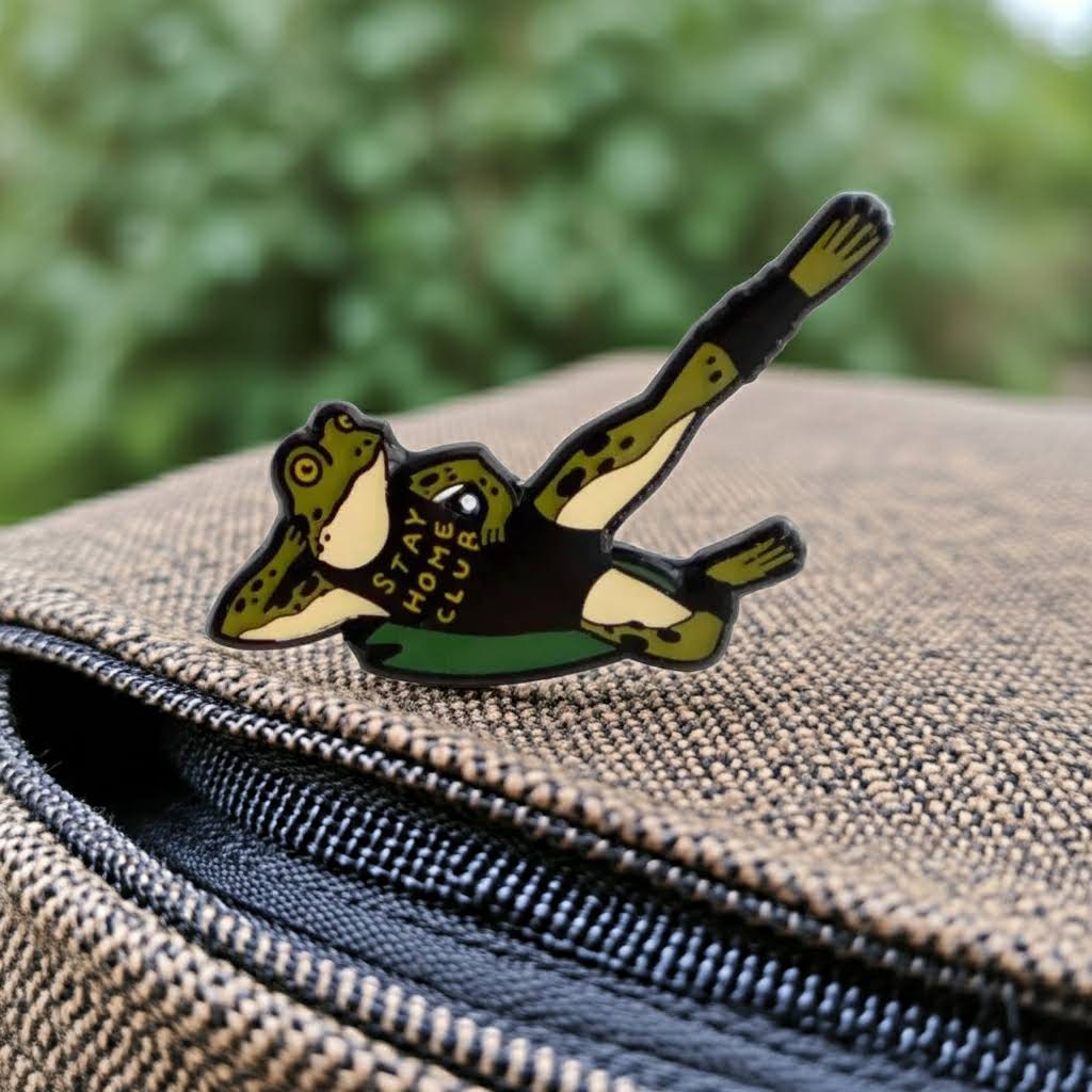 Forager Provisions LTD Stay Home Club enamel pin featuring a green frog doing a workout pose on a textured bag