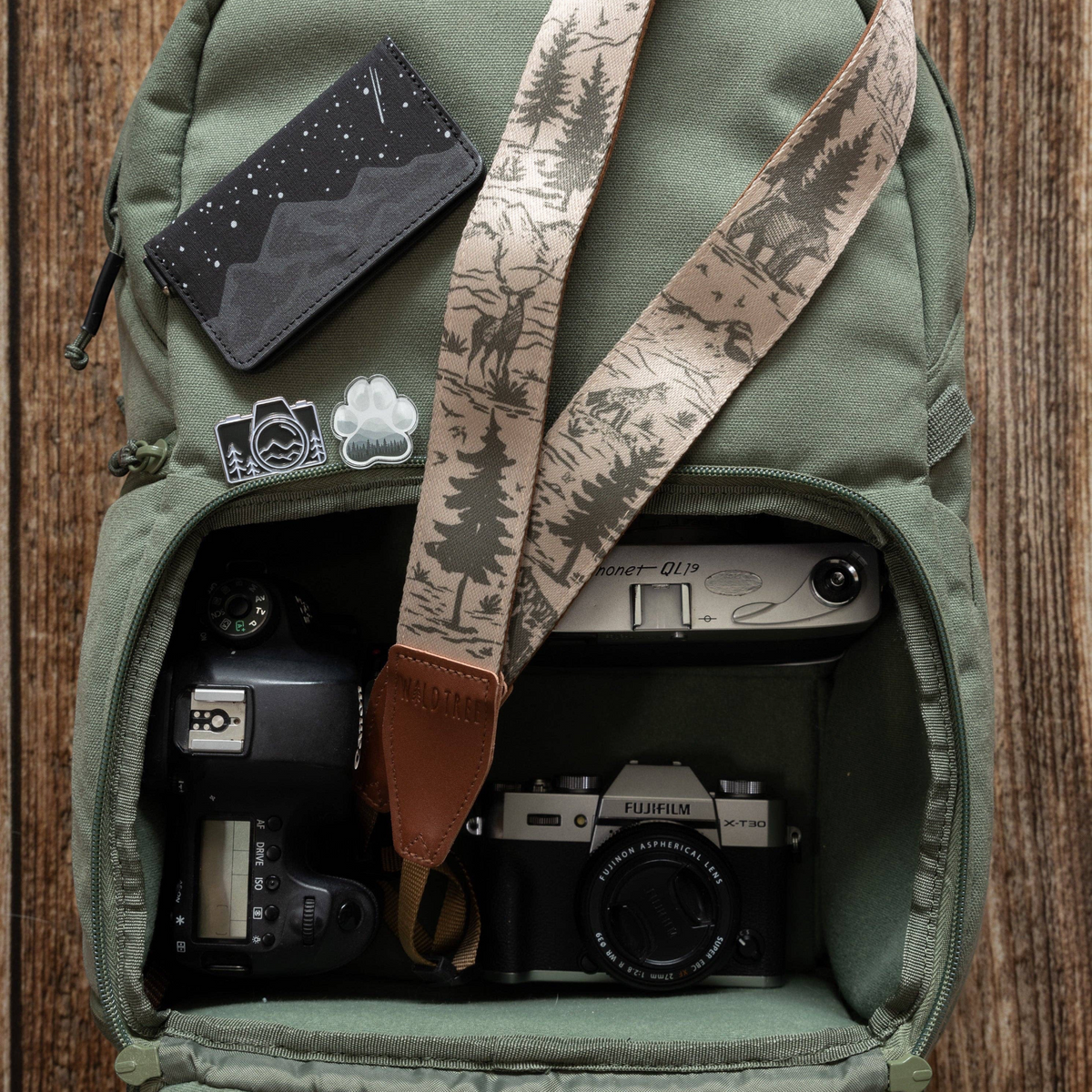 Forager Provisions LTD Wildtree woodland landscape camera strap with mountain and wildlife print inside a green backpack