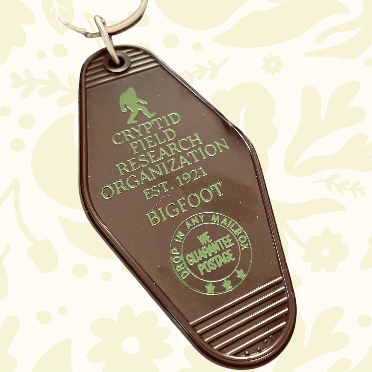 Forager Provisions LTD vintage-style plastic motel key fob featuring a green Bigfoot Cryptid Field Research Org design.