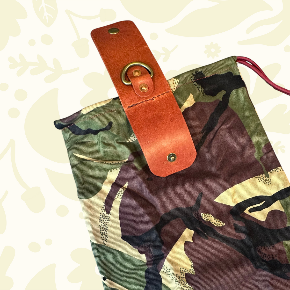 Forager Provisions LTD Kjøtt Supply Co camo forage pouch with leather strap, brass ring, and burgundy drawstring.