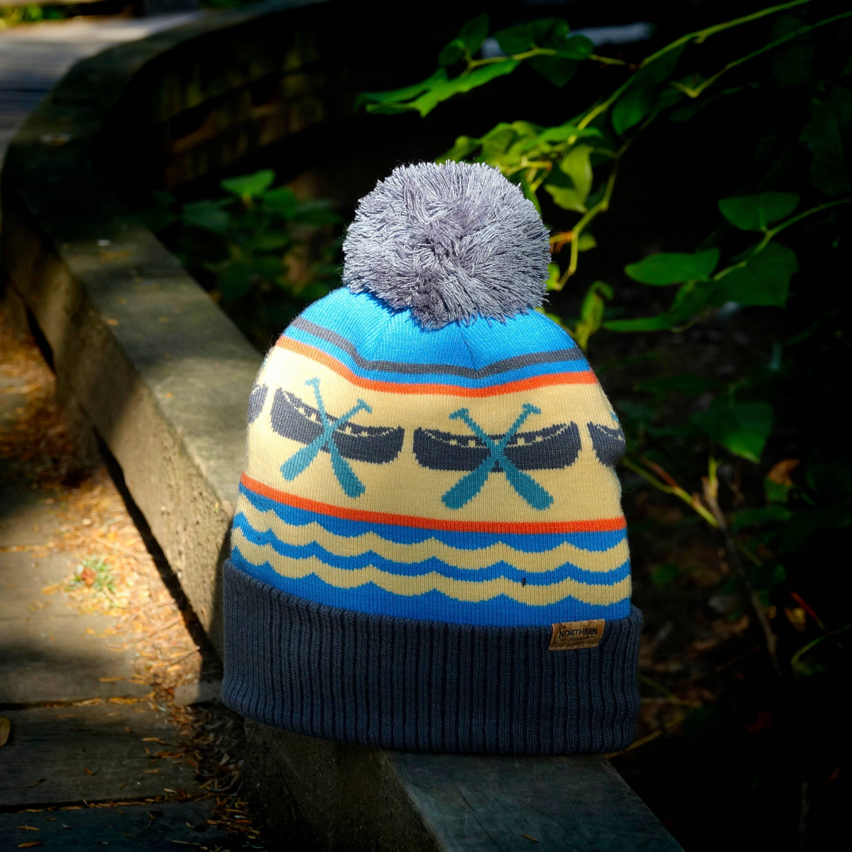 Forager Provisions LTD knit beanie featuring a blue and cream canoe and paddle pattern with a grey pom pom and cuff.