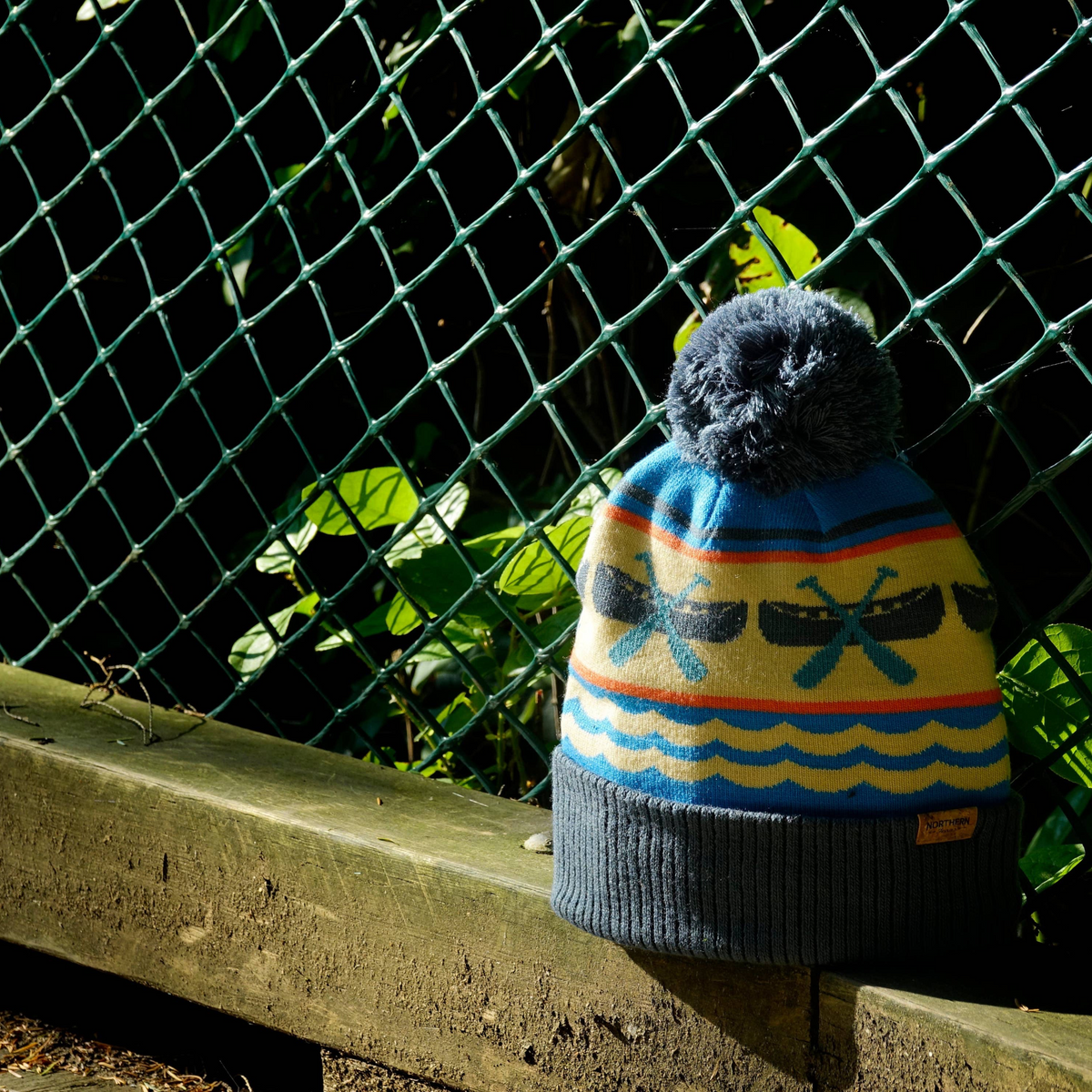 Forager Provisions LTD blue and cream knit beanie featuring canoe and paddle motifs with a fluffy pom pom