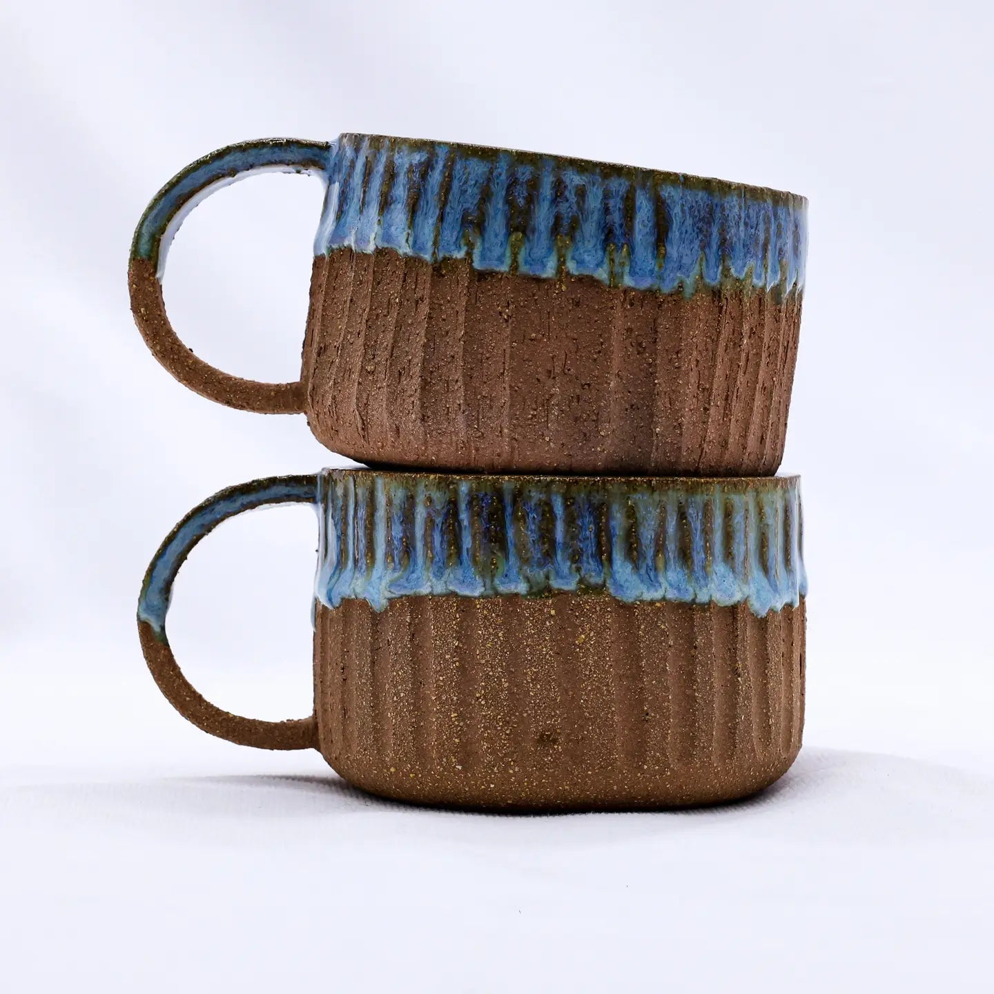 Forager Provisions LTD Ribera Bluvio Arte handmade stoneware mugs stacked, featuring textured brown clay and blue glaze