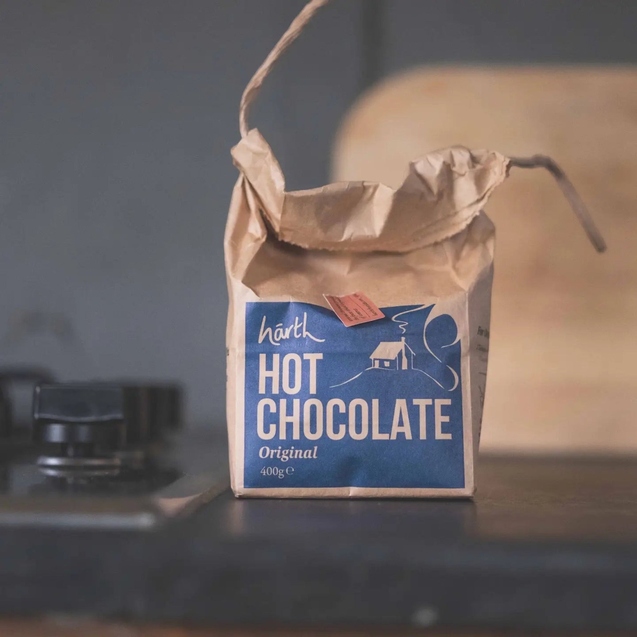 Forager Provisions LTD Harth Original Vegan Hot Chocolate powder in a rustic brown paper bag on a kitchen counter.