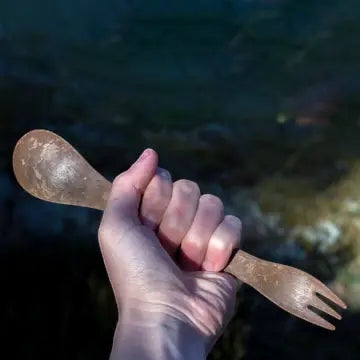 Hand holding Kupilka Spork 225 Long Utensil in brown, eco-friendly natural fibre composite camping spork used outdoors.