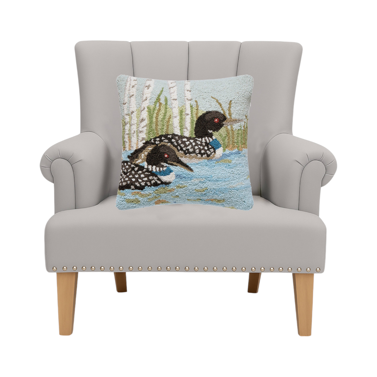 Forager Provisions LTD Peking Handicraft loon wool hooked cushion on a grey armchair in a cabin-style setting.