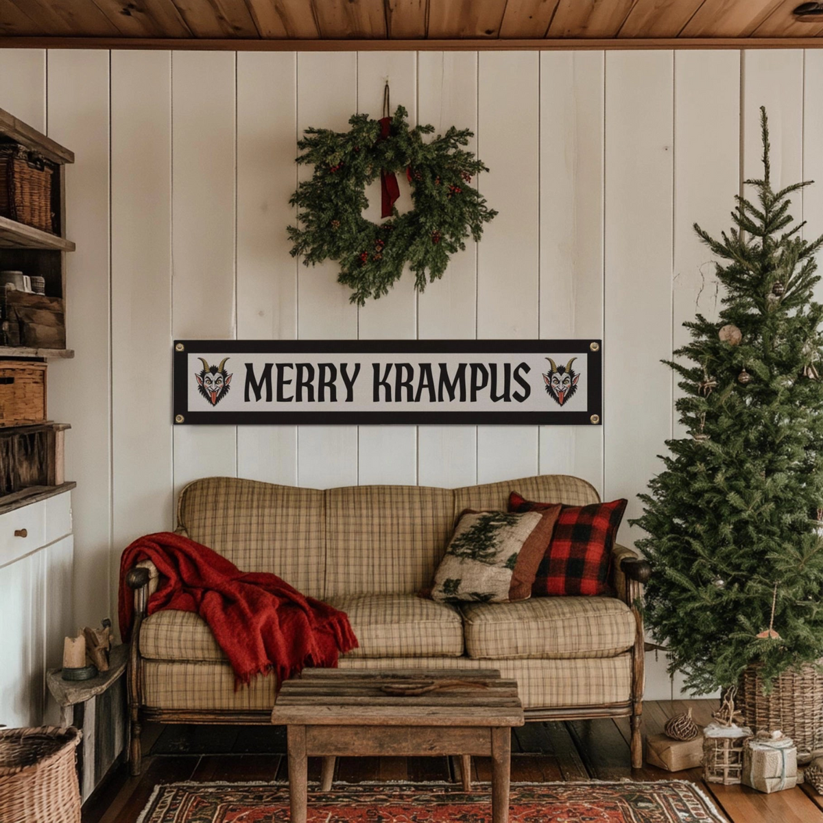 Forager Provisions LTD Merry Krampus felt pennant banner hanging on a white wall above a plaid sofa in a rustic room.