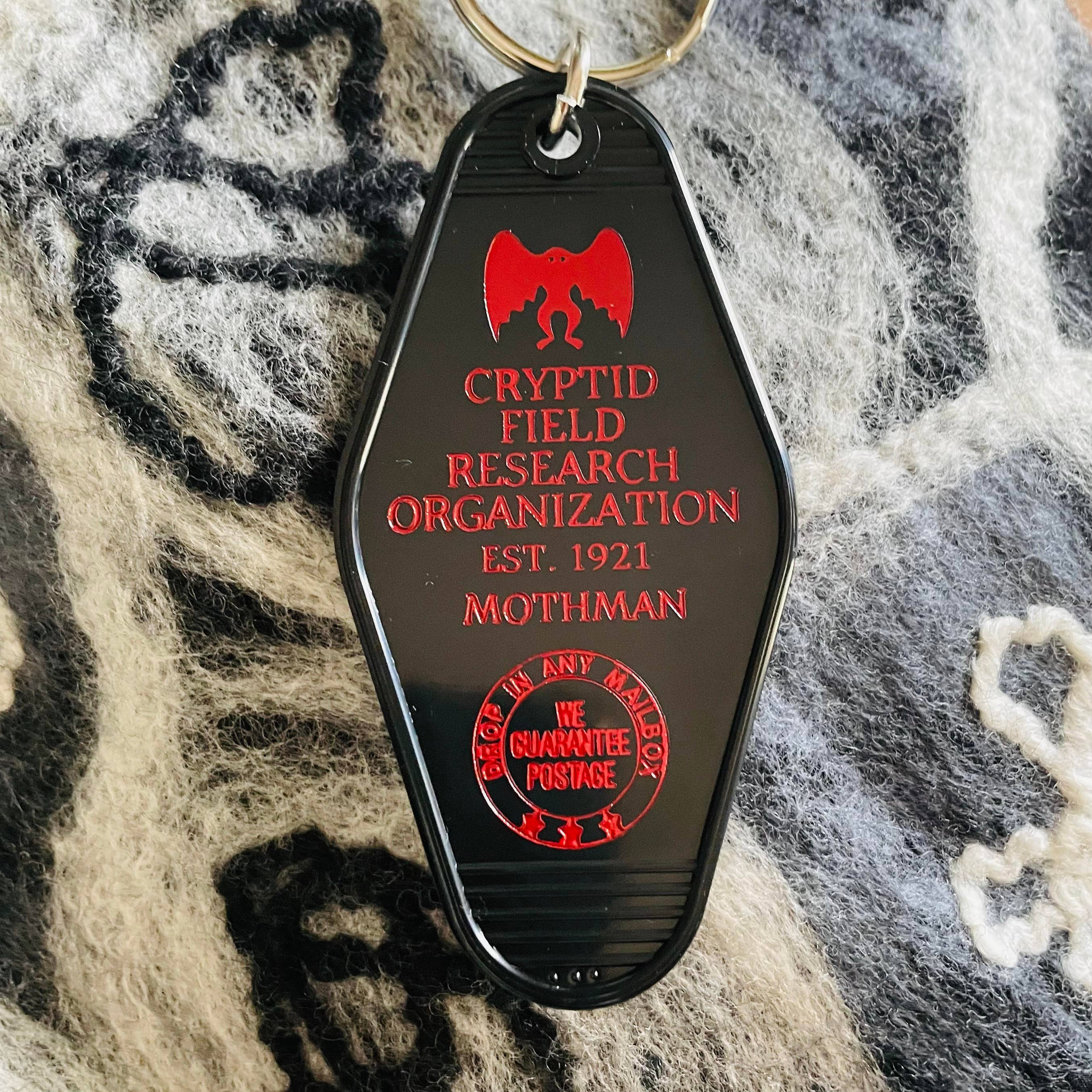 Forager Provisions LTD vintage style black plastic motel key fob featuring a red Mothman cryptid research design.