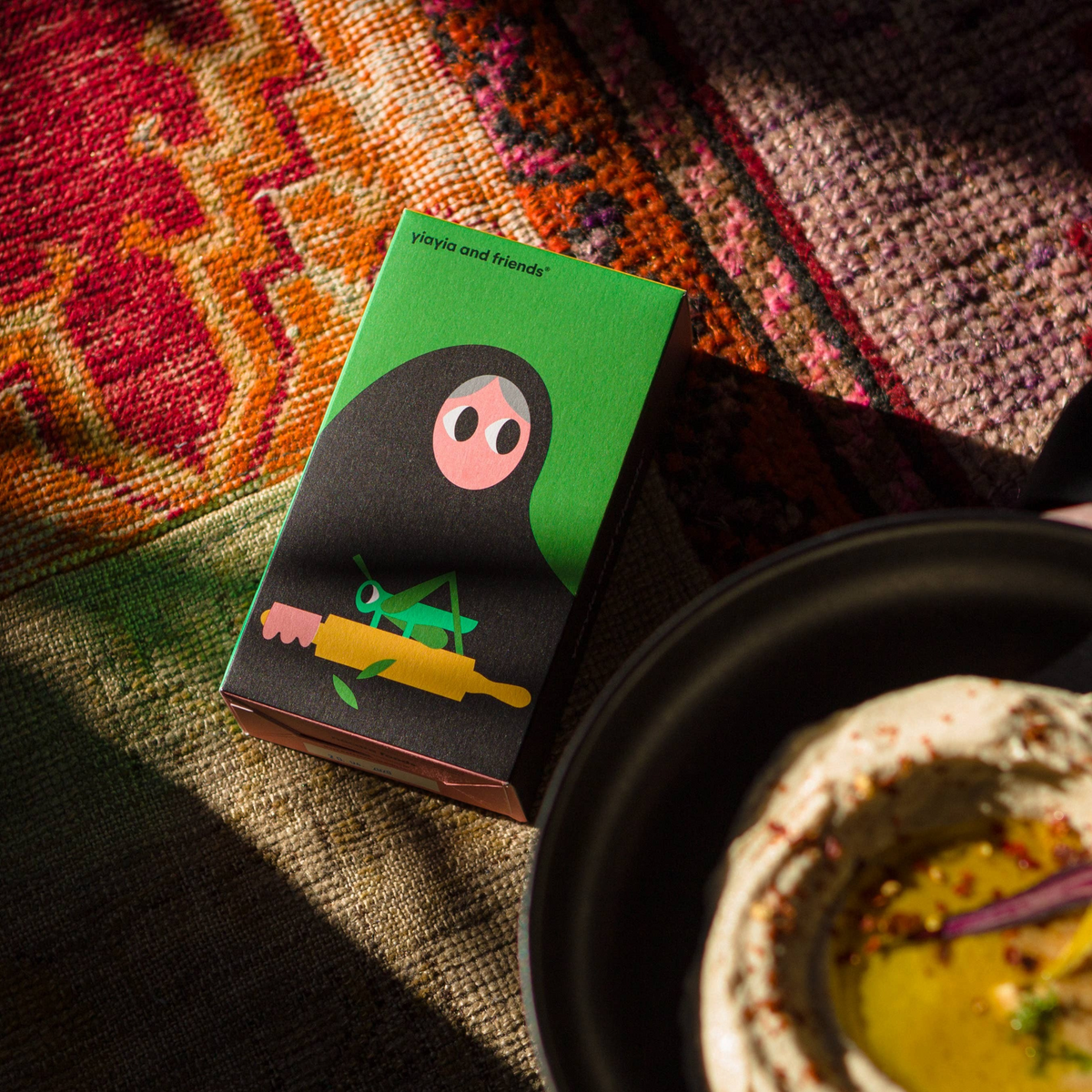 Forager Provisions LTD olive oil and oregano rusks box with illustrated character next to a bowl of dip on a rug