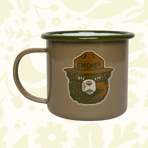 Forager Provisions LTD olive enamel mug featuring a Smokey Bear graphic, perfect for outdoor camping and coffee.