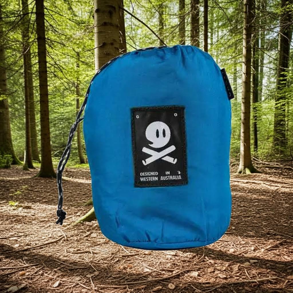 Forager Provisions LTD Ghost Outdoors peacock blue packable travel hammock in its compact storage bag in a forest.