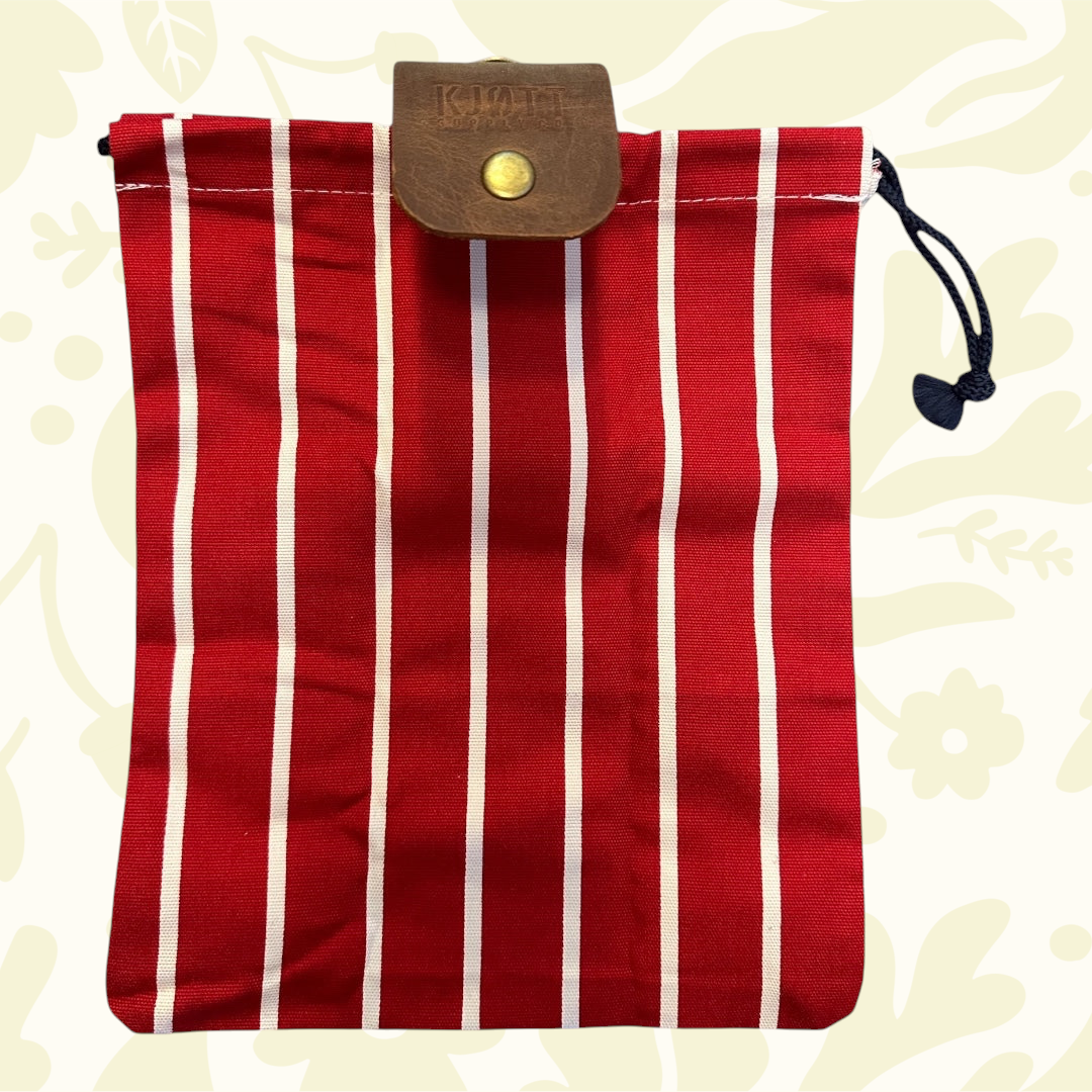 Forager Provisions LTD red forager bag with white stripes, black drawstring, leather flap—stylish outdoor storage pack.