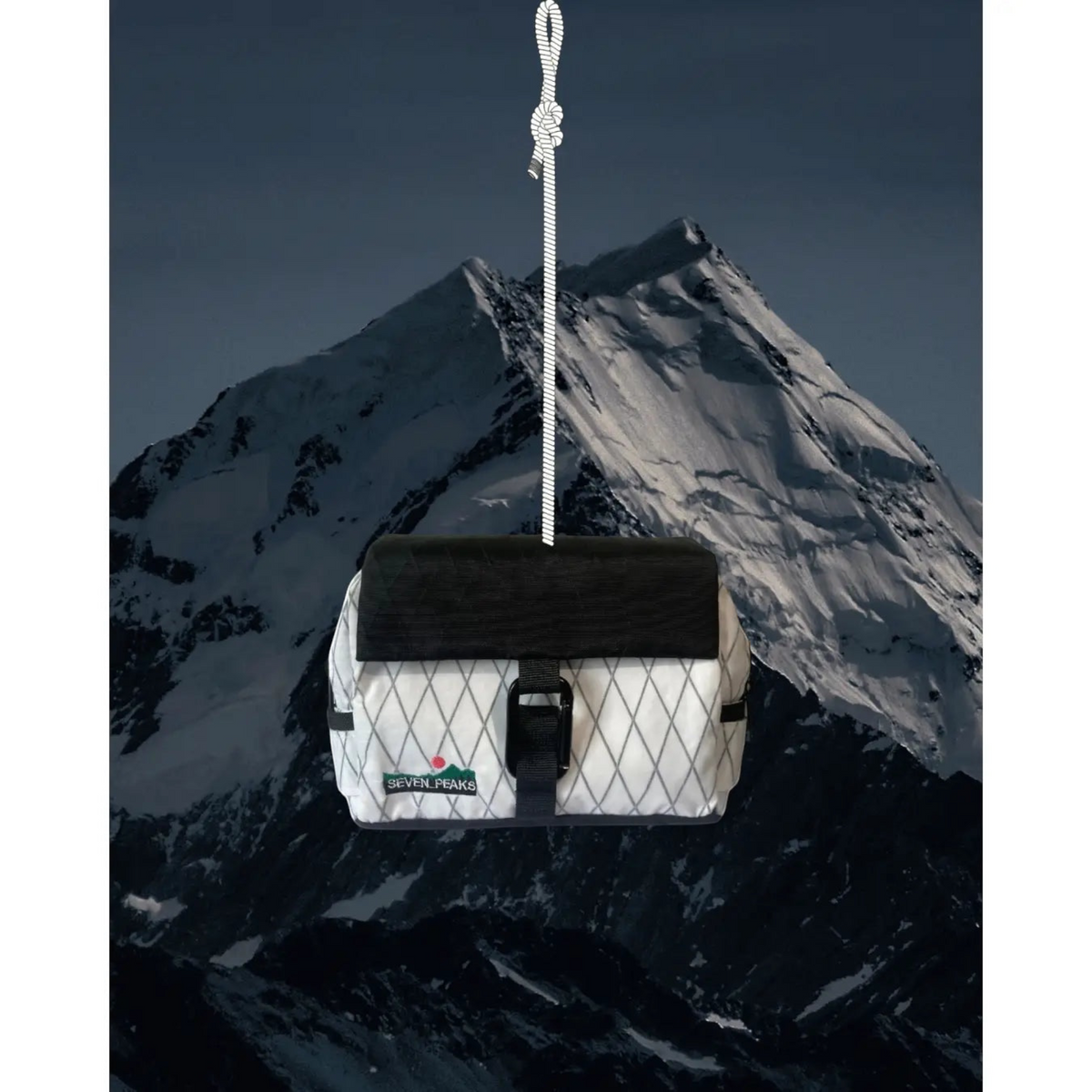 Forager Provisions LTD Seven Peaks black and white water-resistant fanny pack hanging against a mountain backdrop.