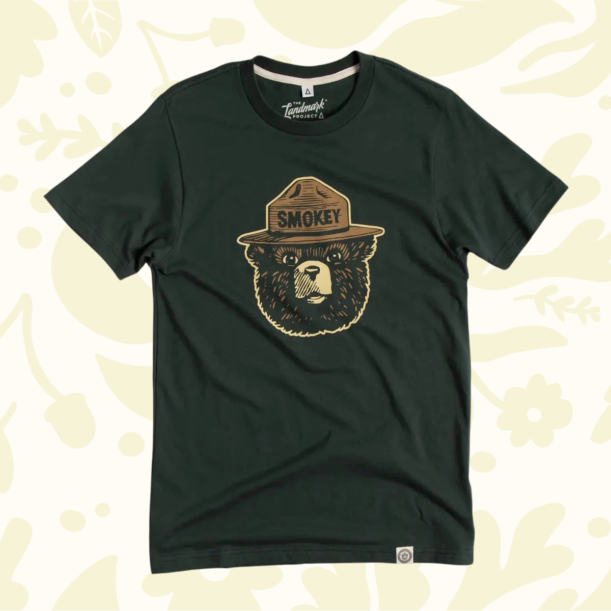 Forager Provisions LTD pine green unisex t-shirt featuring the classic Smokey Bear logo graphic on the chest.
