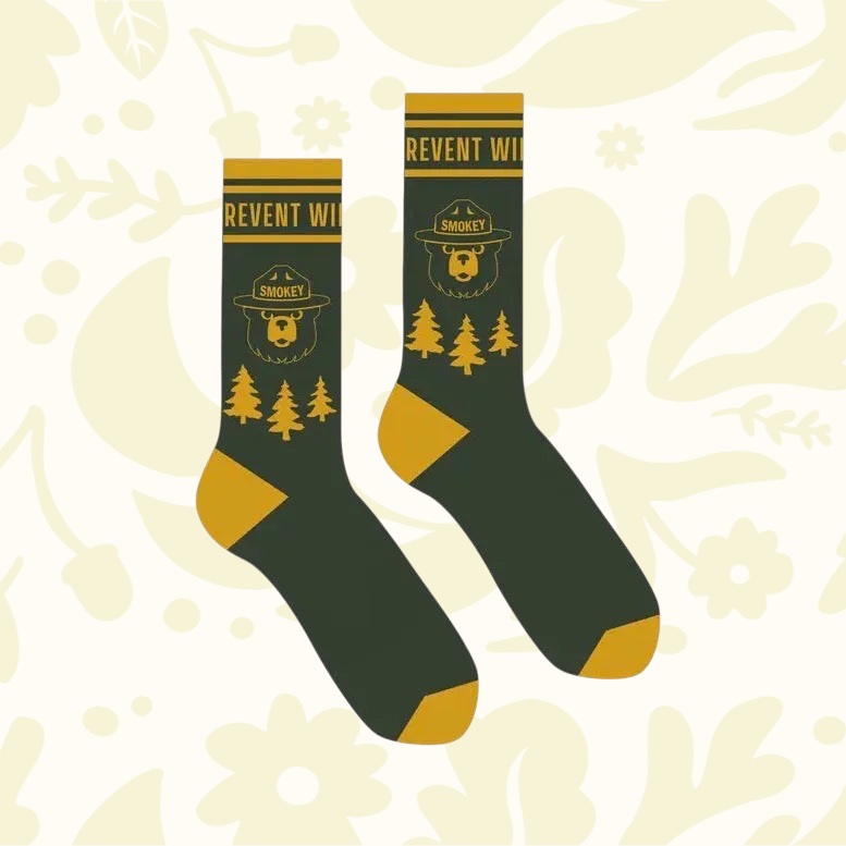 Forager Provisions LTD pine green crew socks featuring a Smokey Bear emblem and forest graphic design.