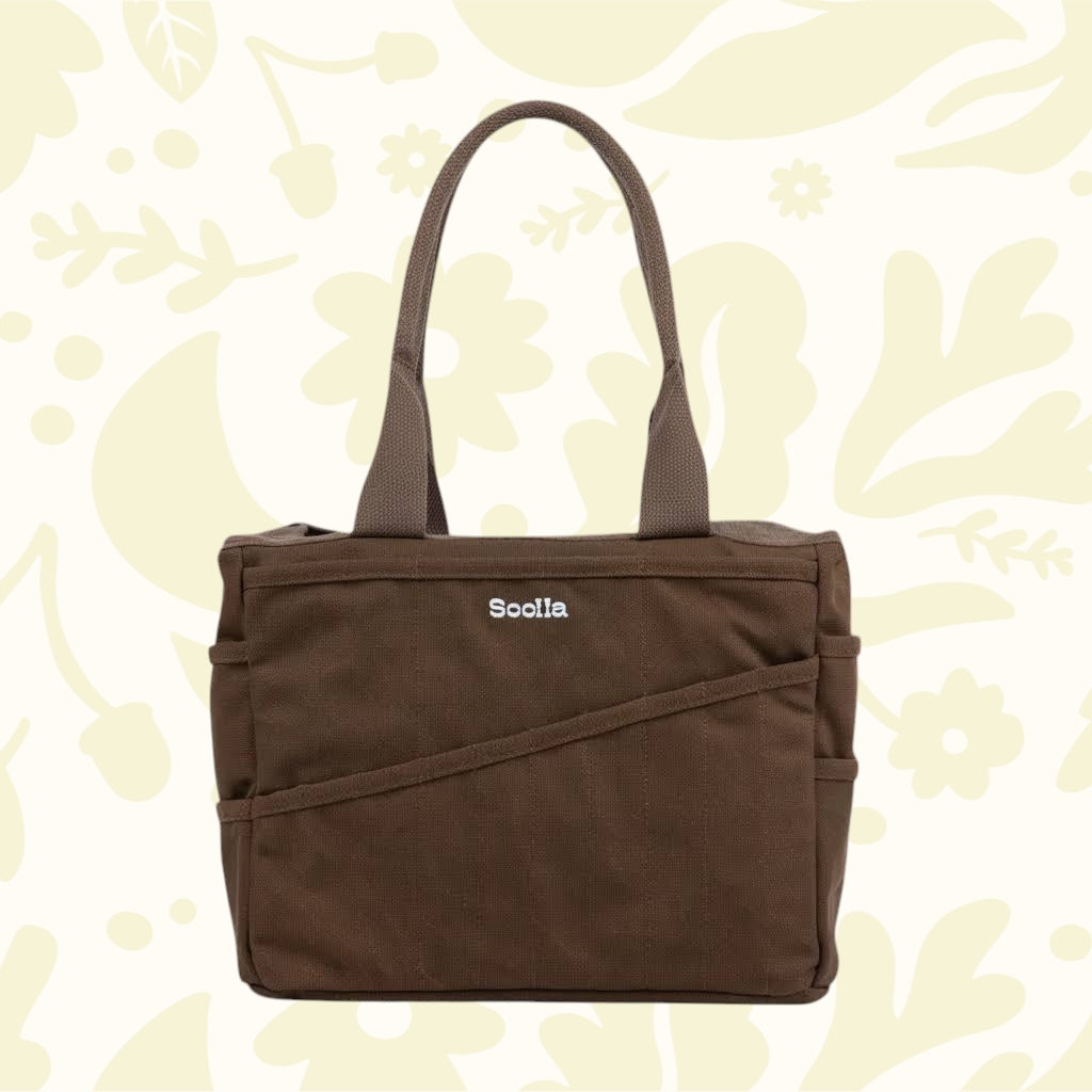 Soolla Studio Pottery Artist Bag in Coffee Bean with two handles, displayed on a light floral background for stylish storage.