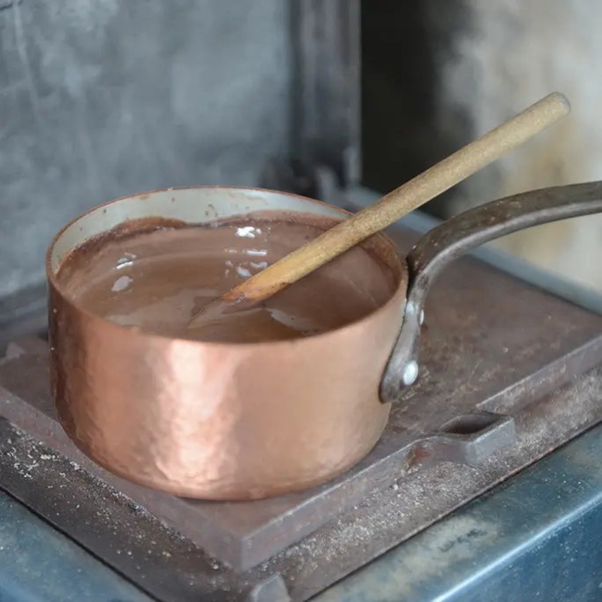 Forager Provisions LTD Harth vegan hot chocolate warming in a rustic copper saucepan on a stove with a wooden spoon