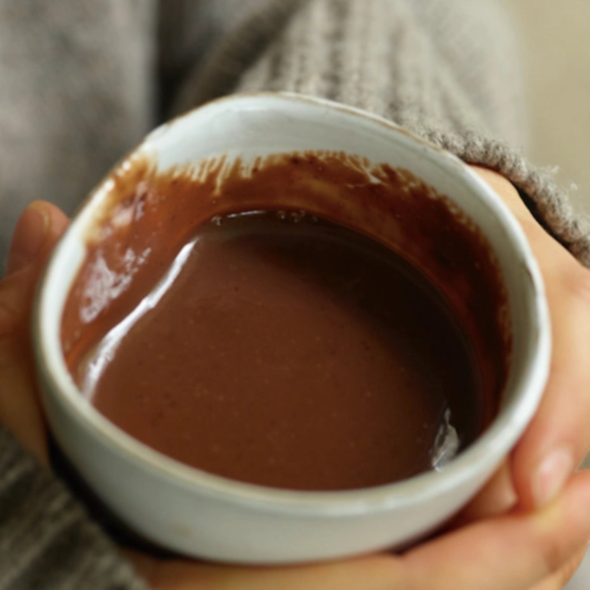 Forager Provisions LTD Harth vegan hot chocolate in a ceramic mug held by hands in a cosy grey knitted sweater