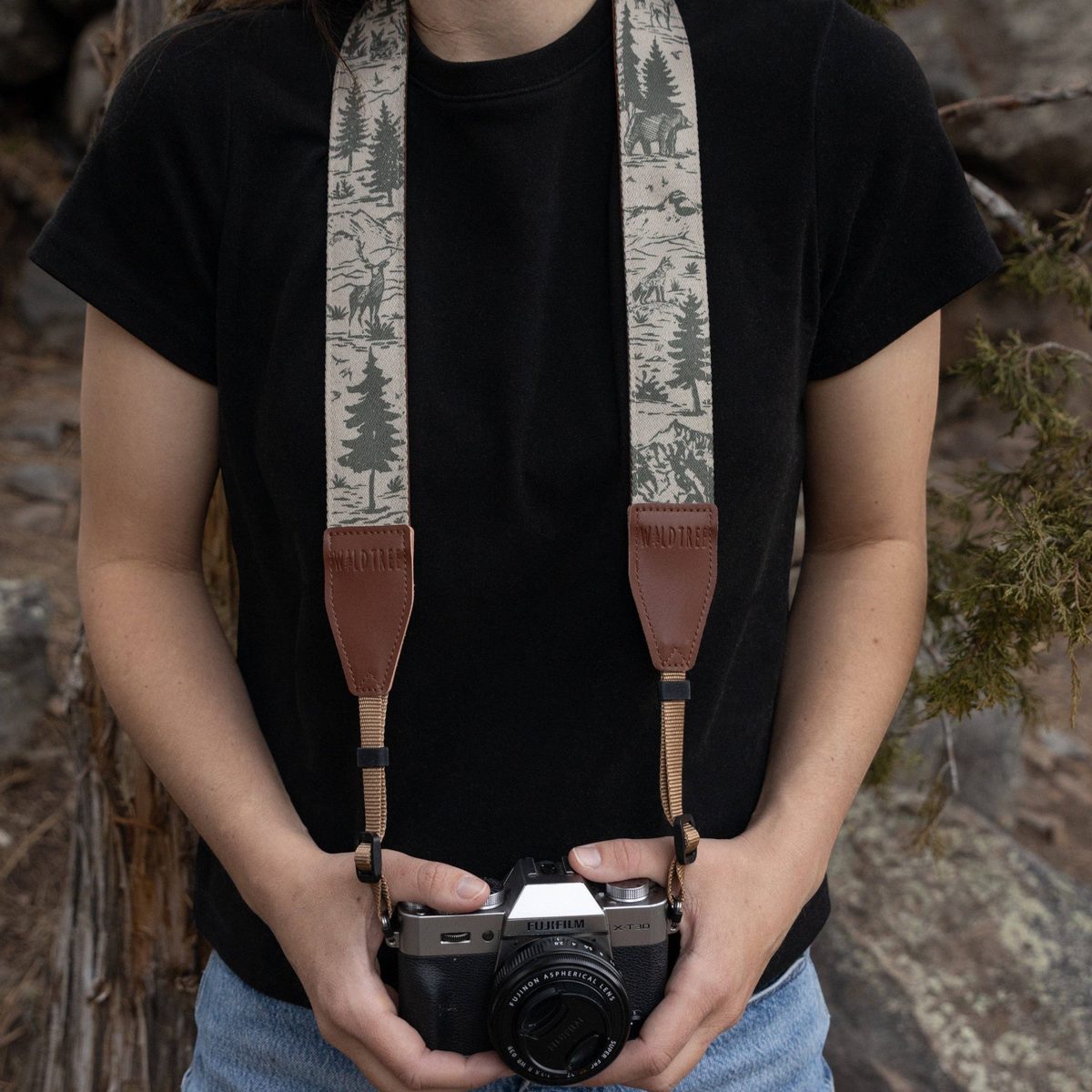 Forager Provisions LTD Wildtree camera strap with woodland mountain print, worn by a person with a Fujifilm camera.