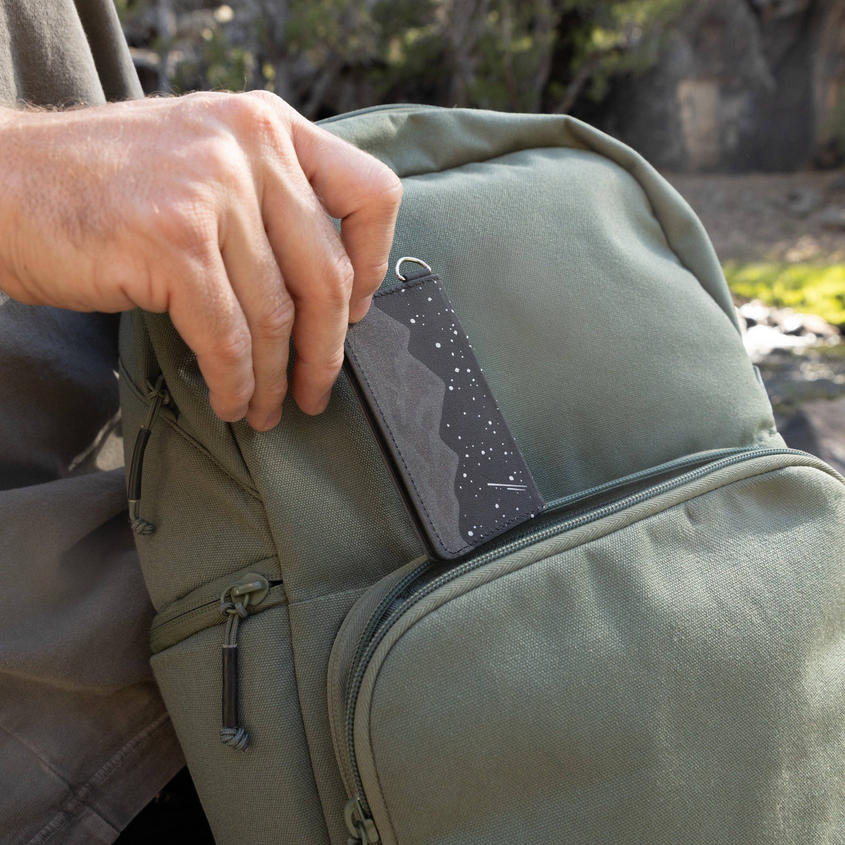 Forager Provisions LTD Wildtree Midnight Mountain card holder being placed into an olive green backpack pocket