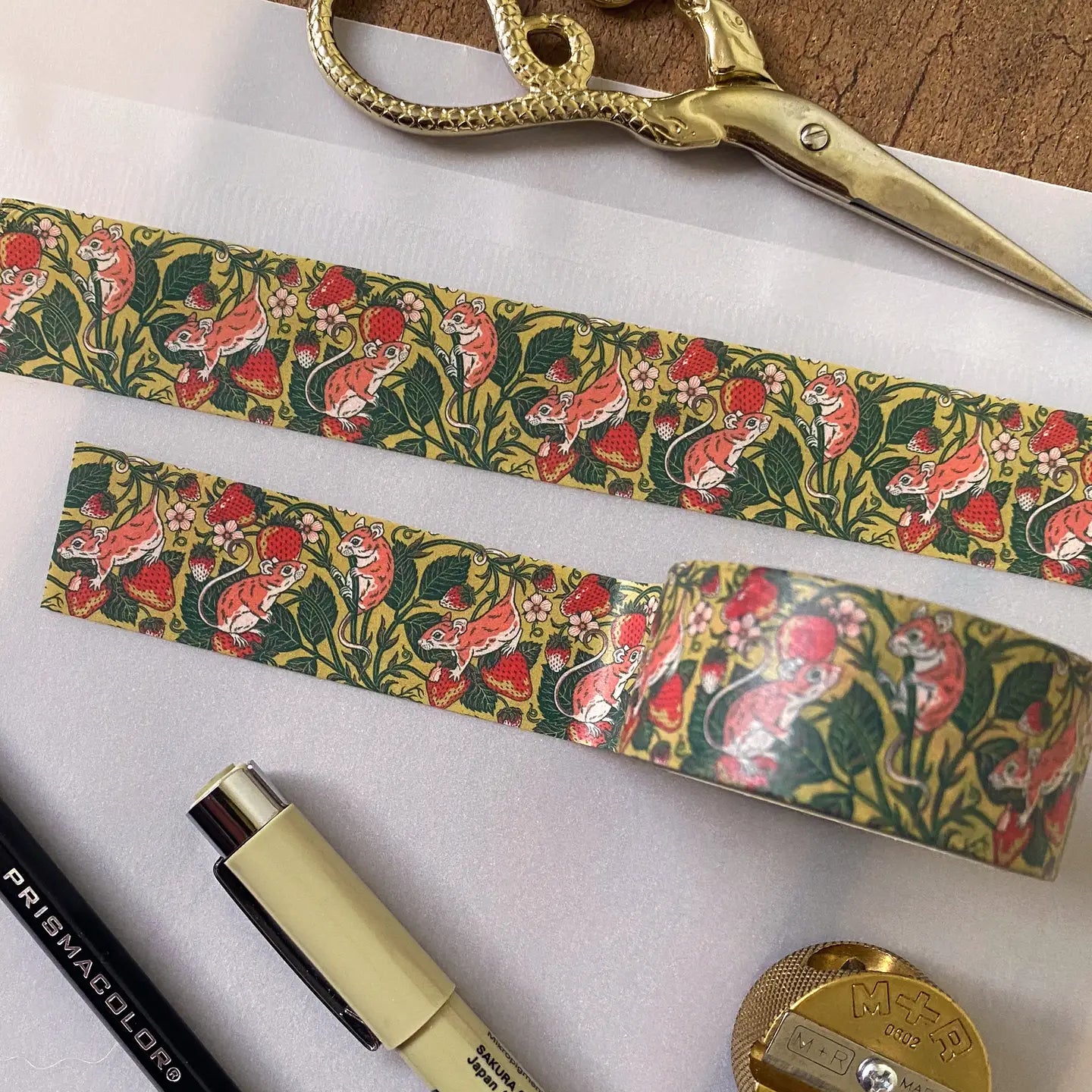 Kate O’Hara Strawberry Mouse Washi Tape, gold scissors, pens, and a sharpener arranged neatly on a white background.