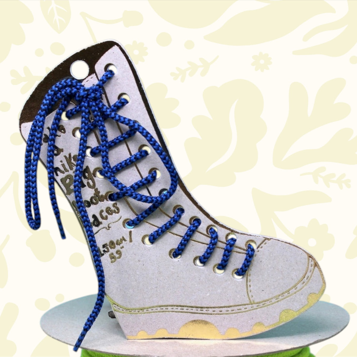 Blue Ark boot with large blue laces rests on bright green cord, set against a cloudy sky—trendy footwear fashion photo.