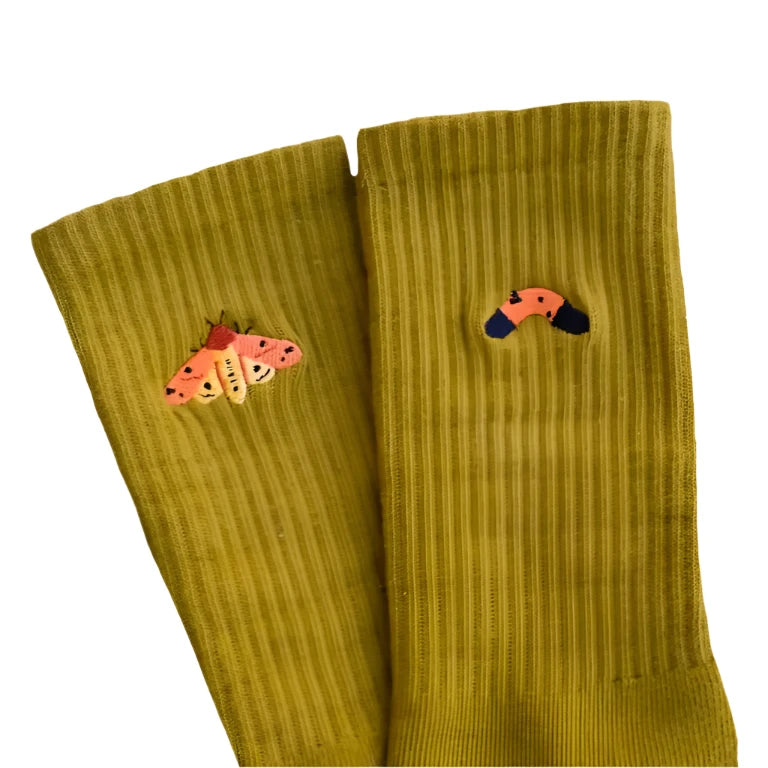Pair of Olive socks with embroidered moths on a beige background