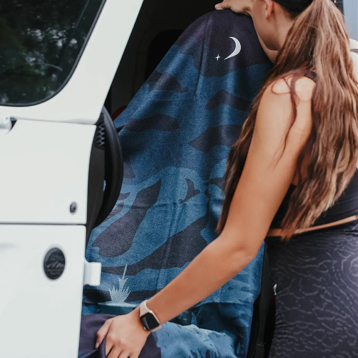 Forager Provisions LTD Sprints Nightfall Grizzly car seat towel with moon and forest print being placed on a car seat