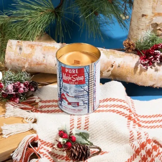 Seracon Maple Syrup Candle in signature tin on cozy orange-white blanket, surrounded by pine, birch, and festive berries.