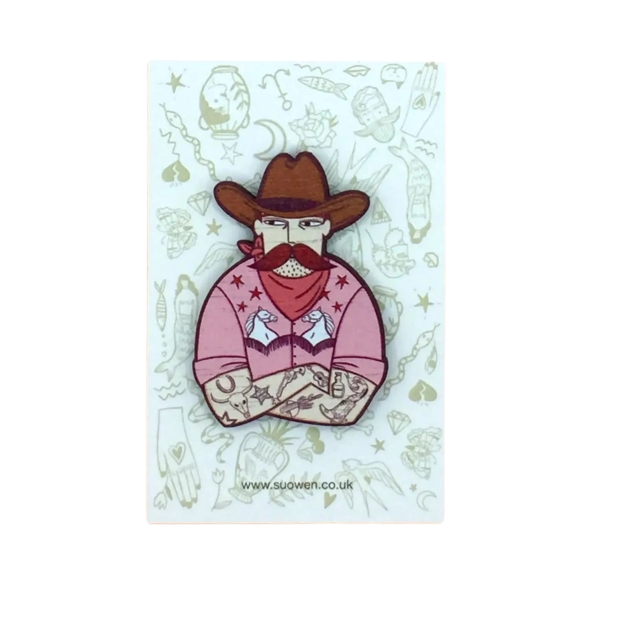 The Su Owen Cowboy Pin Brooch features a tattooed cowboy in a brown hat and beard, dressed in a fashionable fringed shirt adorned with unicorns, set against an illustrated background.