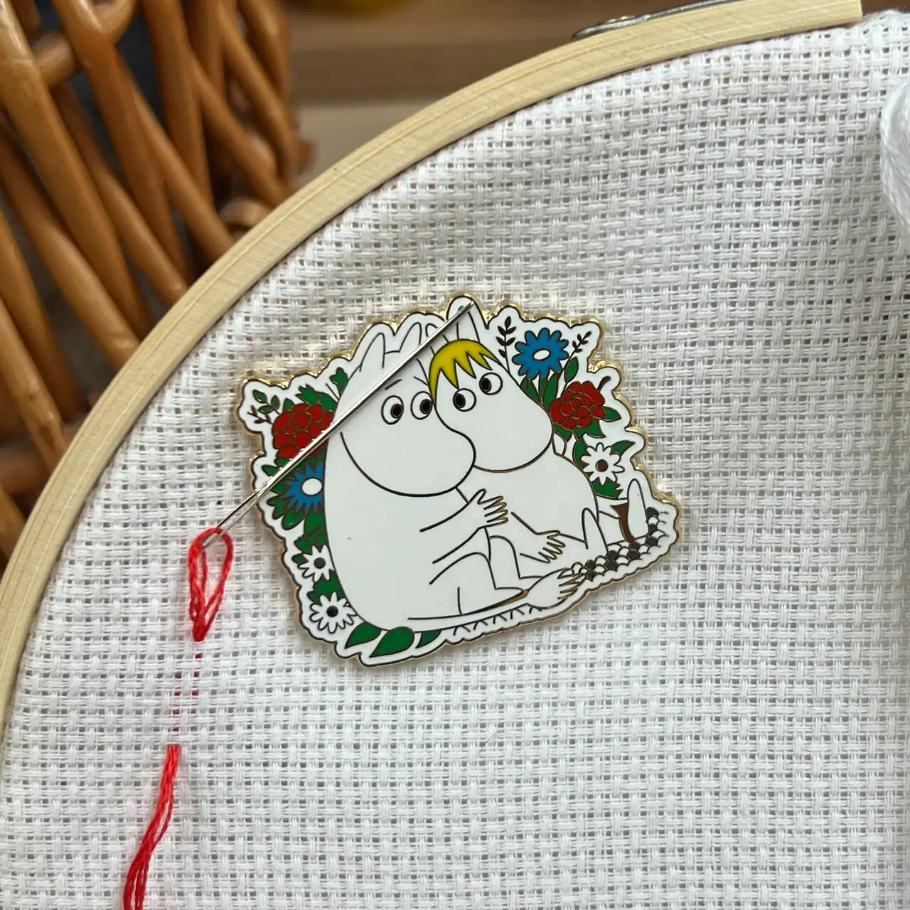 The Crafty Kit Co Moomin Needle Minder features a Little My character with a mischievous expression, dressed in red and holding a needle with pink thread. This charming embroidery accessory comes equipped with a strong magnet to keep your project secure.