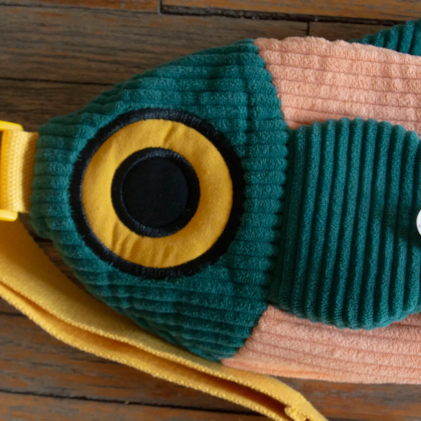 Curlworks The Fish Bag Coral Salmon and Dark Green Crossbody Bag displayed on a wooden surface, trendy accessory by Curlworks.