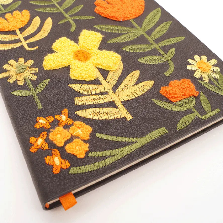 Forager Provisions LTD Denik journal with a black cover featuring textured, chunky folk-style embroidered flowers.