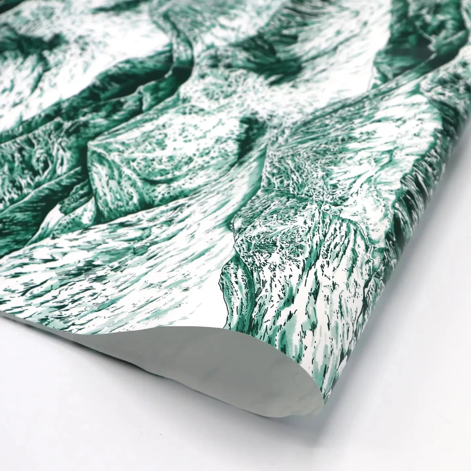 A close-up of a sheet of wrapping paper featuring a detailed, artistic illustration of mountain landscapes in shades of green