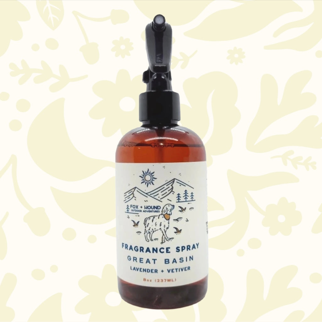 Amber bottle of Fox + Hound Dog Cologne - Great Basin with label depicting a dog, trees, and mountains. Text reads "GREAT BASIN, Lavender + Vetiver." Part of the Outdoor Adventures Collection.
