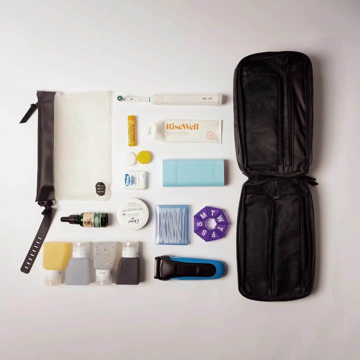 Flat lay of Gravel Explorer Plus Toiletry Bag, travel bottles, and razor on white background—best travel bag essentials.