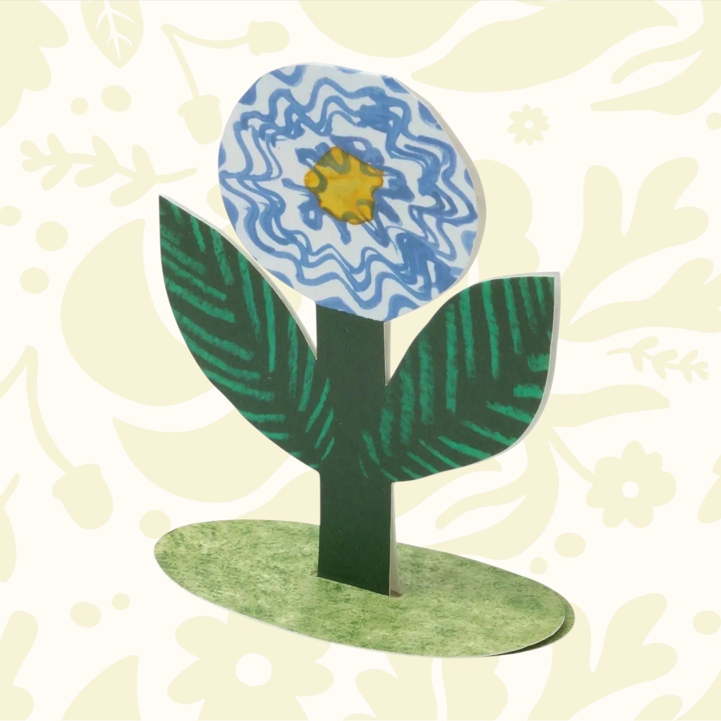 Hadley Paper Goods Blue Flower Stand Up Card with green leaves, blue-yellow blossom on a green oval base—unique floral stationery.