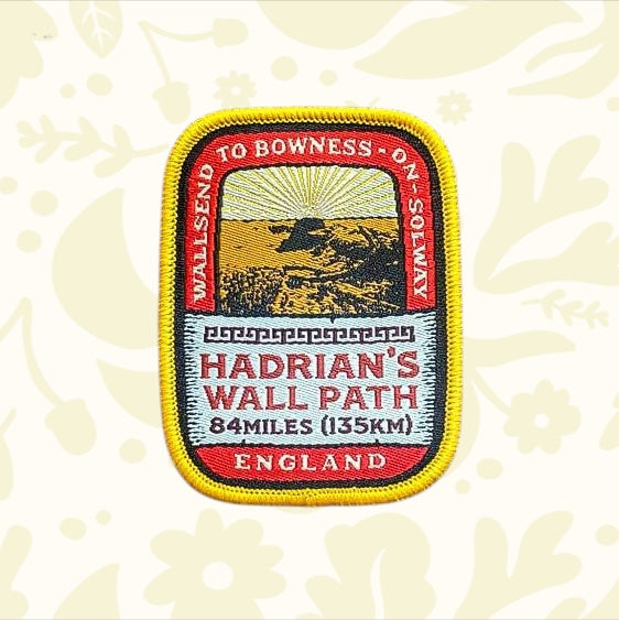 Hadrians Wall Path patch with sunset graphic and England text displayed on wood—Adventure Patch Company collectible badge.
