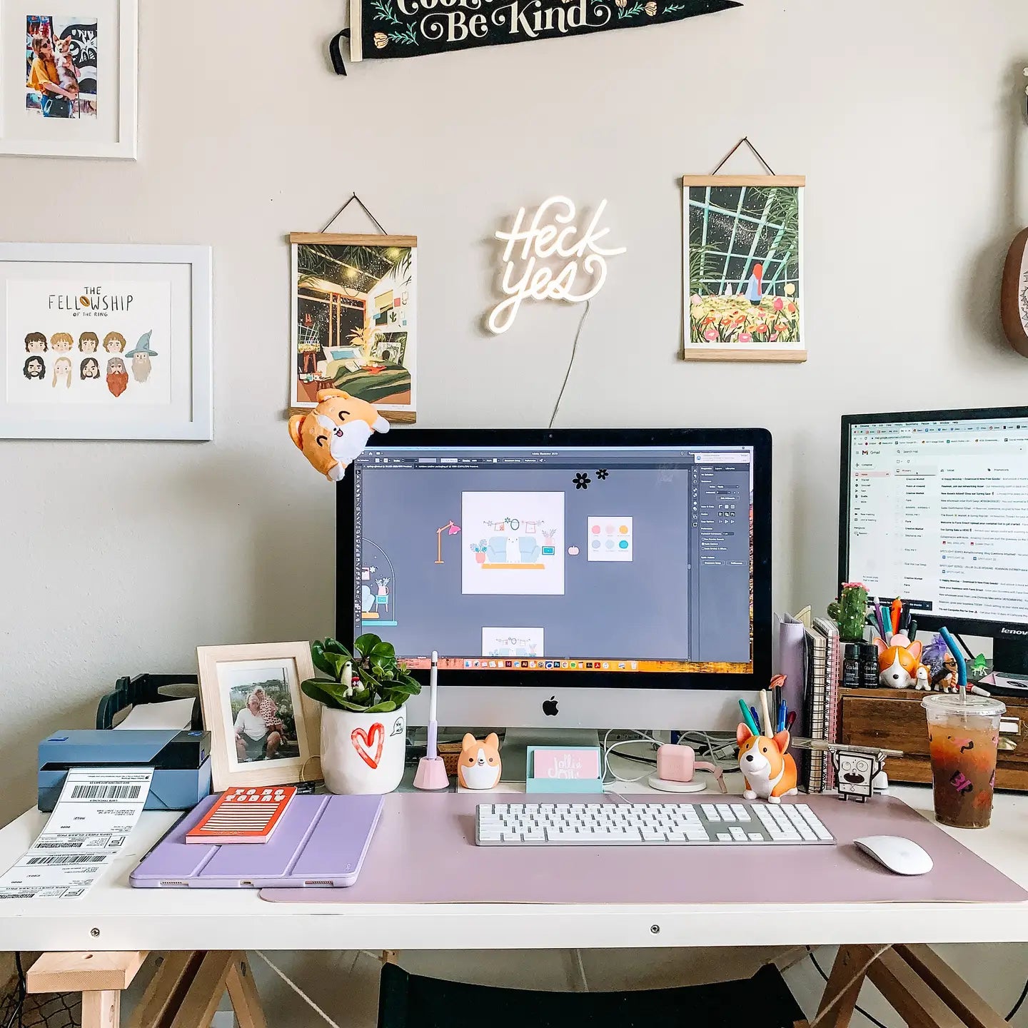 Large monitor, green plants, and Oxford Pennant Its Cool To Be Kind add vintage charm to a stylish home office workspace.