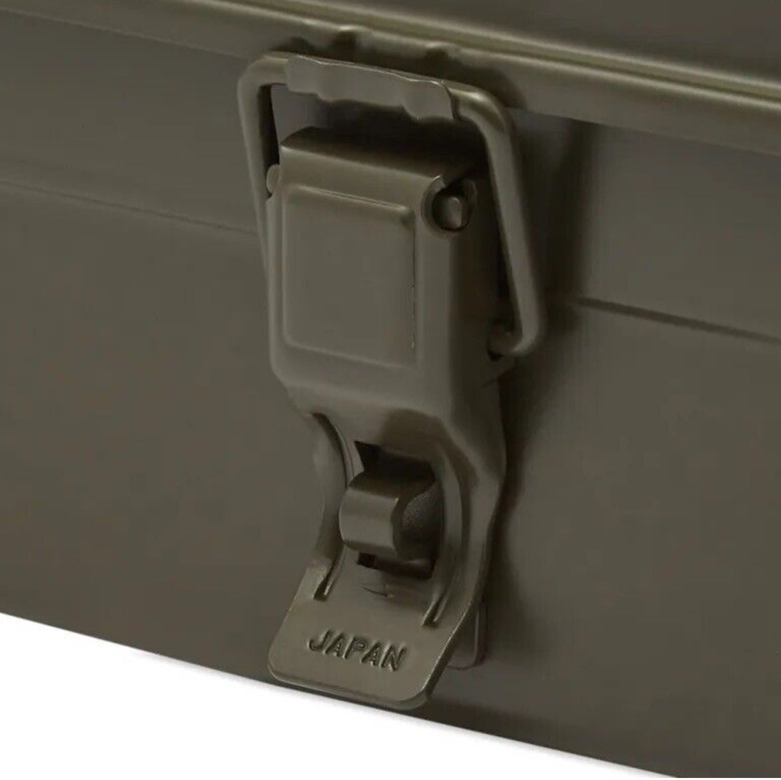 Close-up of a metal latch on a khaki Trusco utility toolbox, with the word "JAPAN" embossed at the bottom of the latch, showcasing the quality craftsmanship typical of Trusco toolboxes.