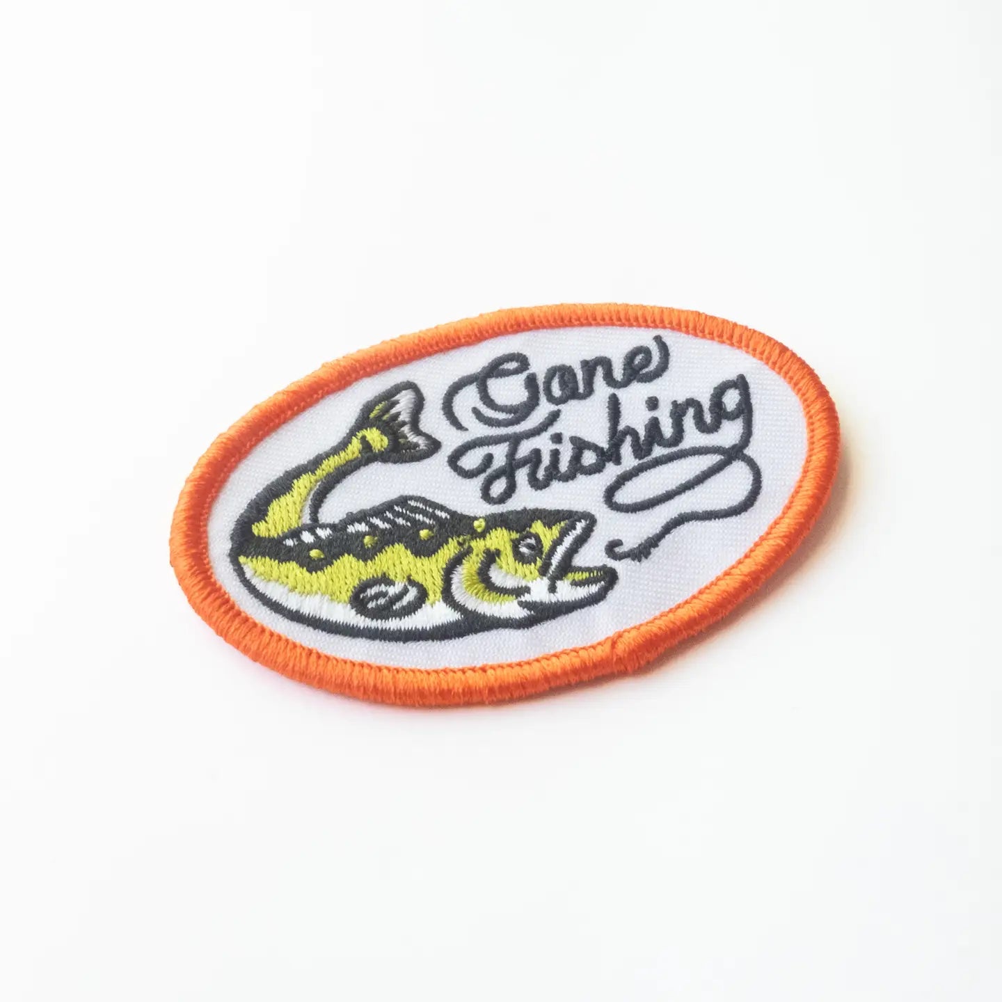Union Made Oval Embroidered Iron On Patch, Gone Fishing design with fish, orange border, bold text on white. Perfect for jackets.
