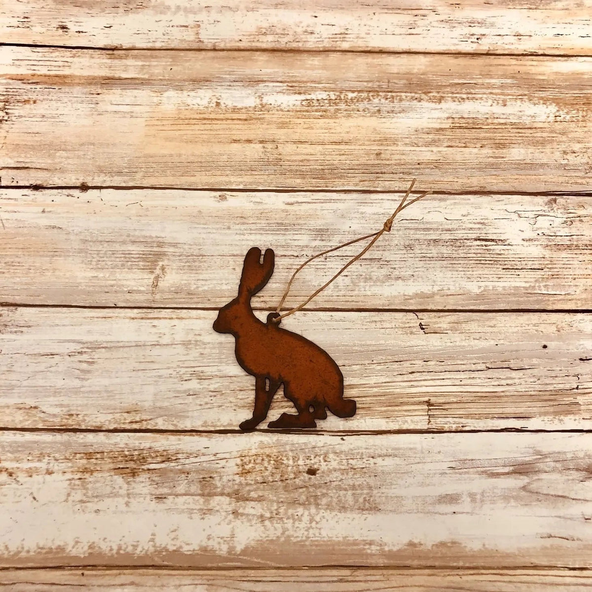 Universal Ironworks rust color Jack Rabbit hanging decoration displayed on a weathered wooden surface for rustic home décor.