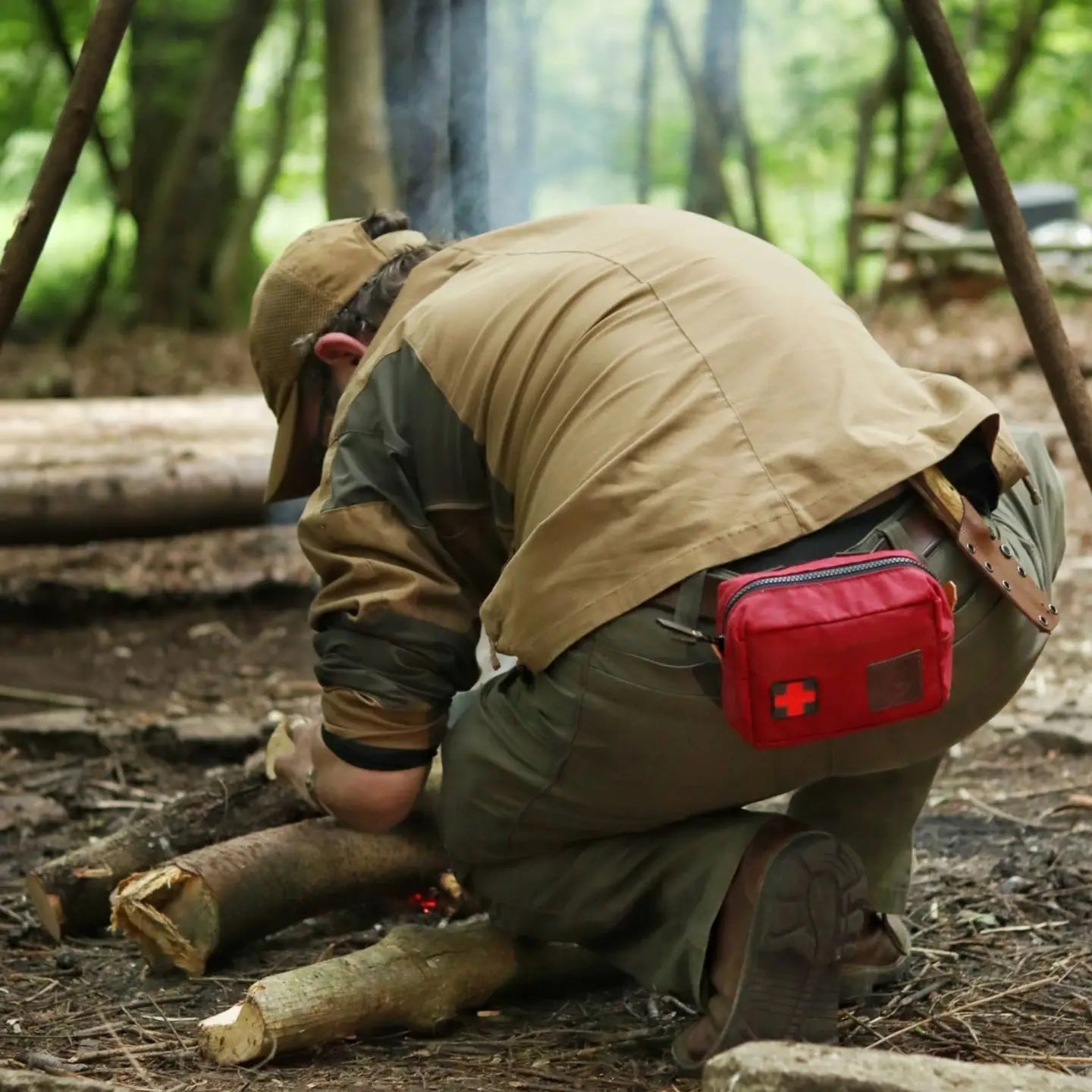Camper wearing Journeyman Craft First Aid Kit Belt adjusts firewood at night campfire in forest, outdoor safety gear visible.
