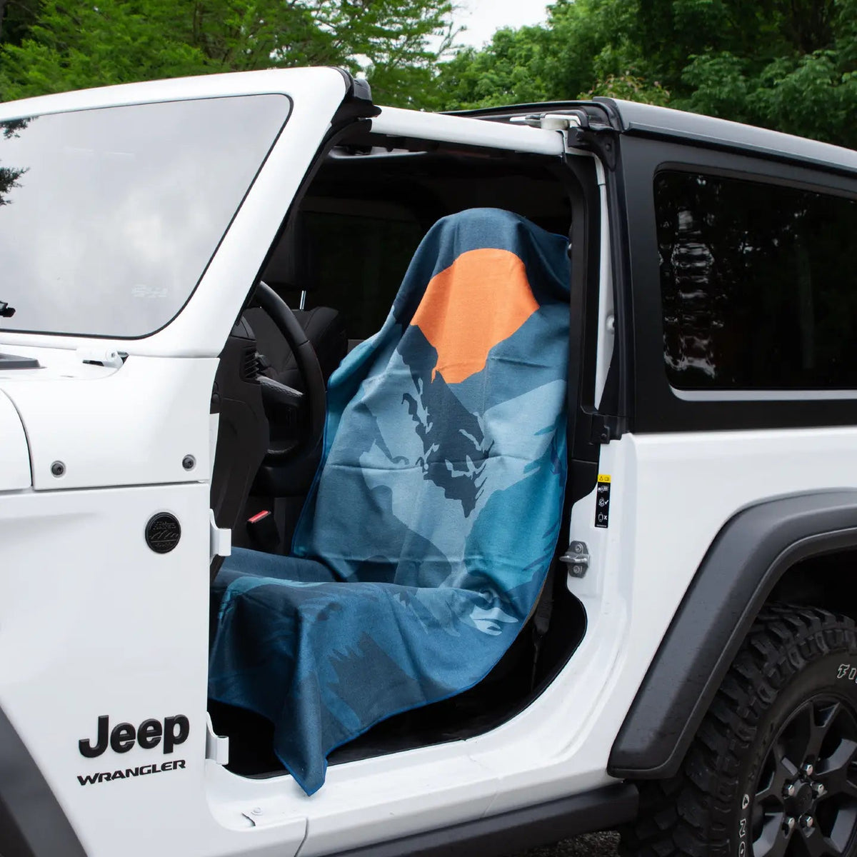Forager Provisions LTD Sprints Sasquatch Habitat car seat towel with blue forest print and orange sun in a white Jeep