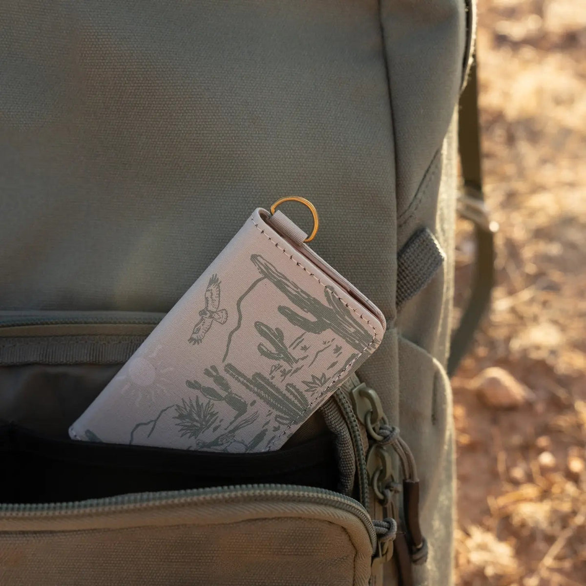 Forager Provisions LTD Wildtree card holder with western landscape print tucked into an olive green backpack pocket.